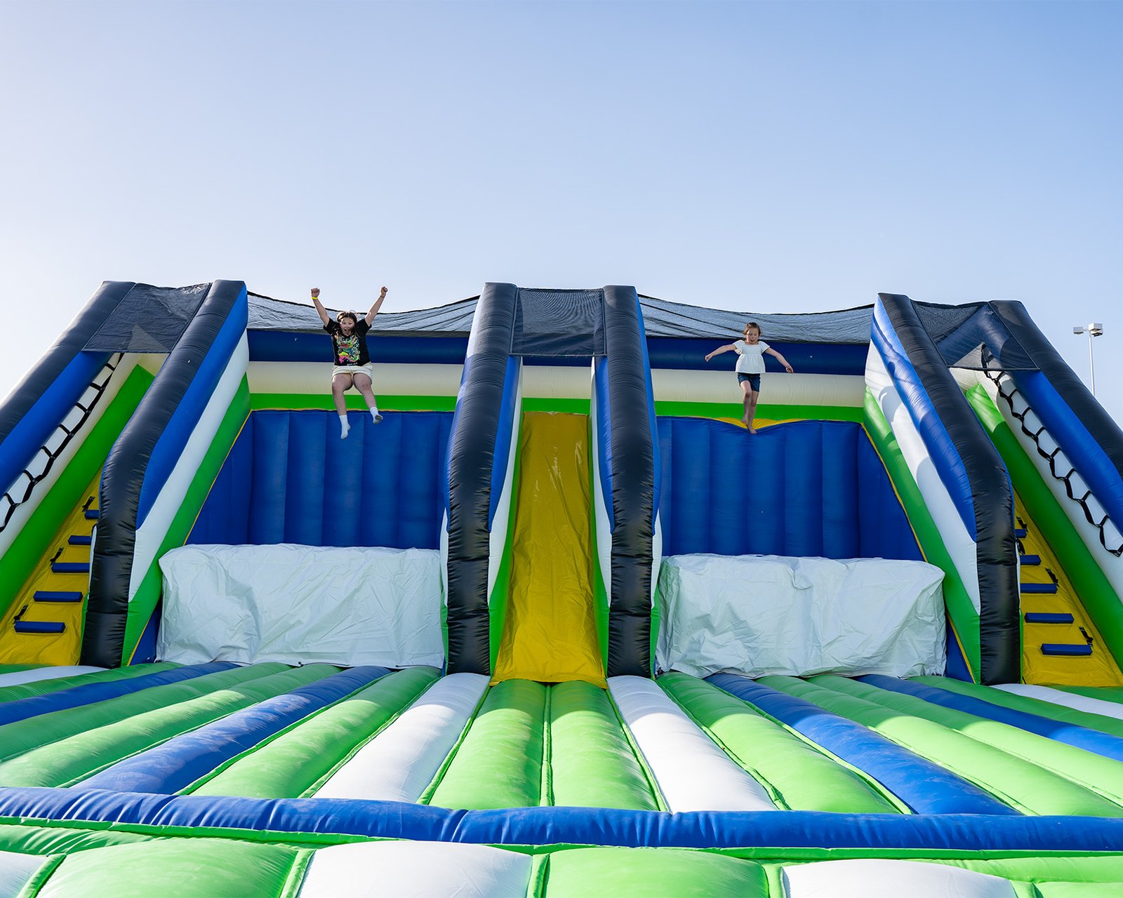 Two girls jumping off platforms onto giant air bags at one of the world's largest bounce houses