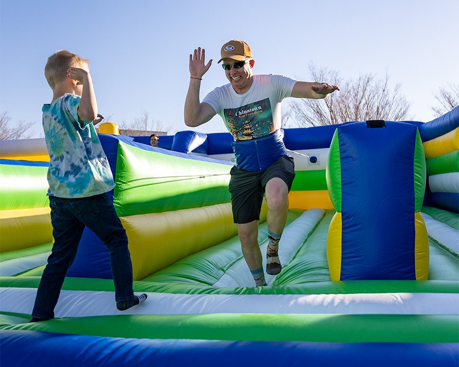 Man high fiving his son while playing a bungee game at one of the world's largest bounce houses
