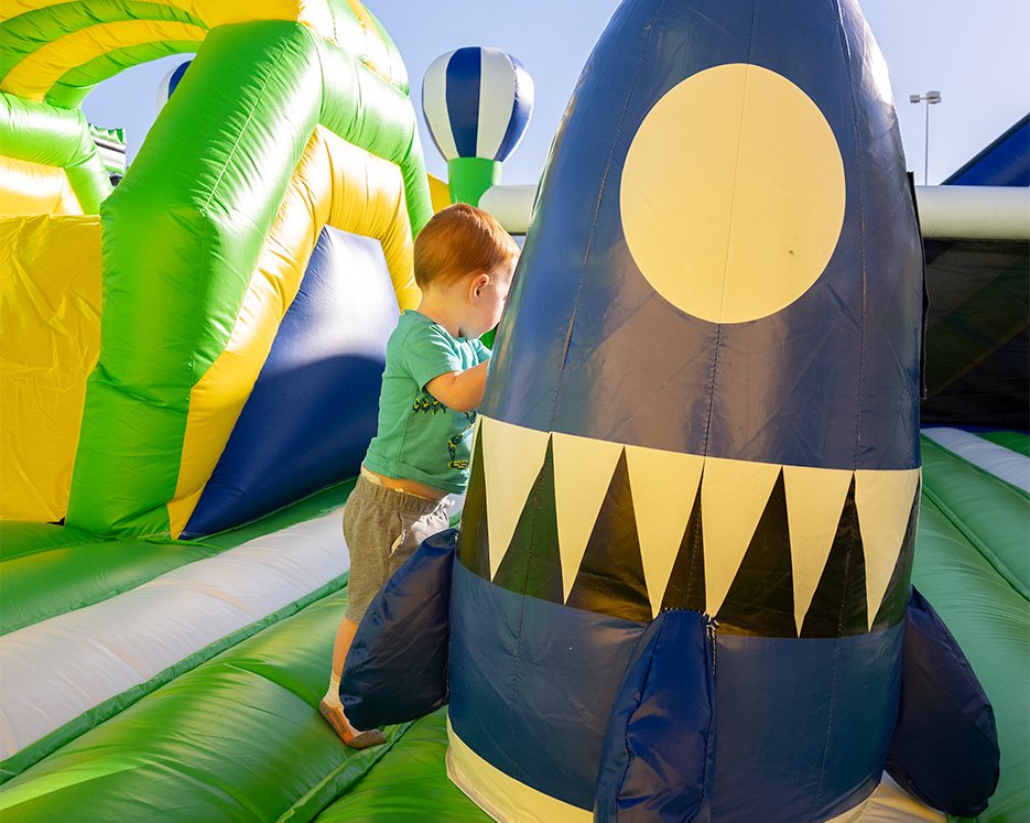 Little boy playing by inflatable space ship on one of the world's largest bounce houses