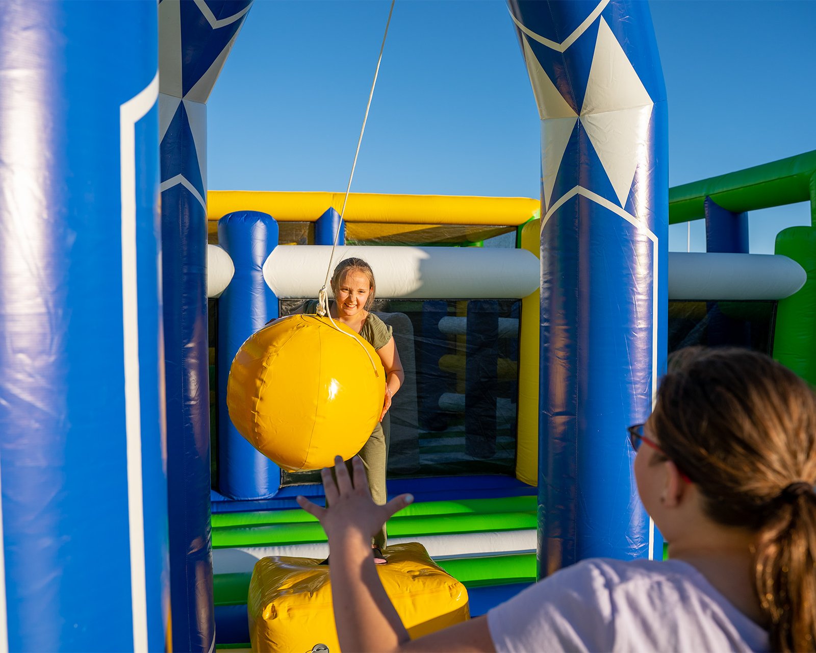 Young girls playing an inflatable wrecking ball game on one of the world's largest bounce houses